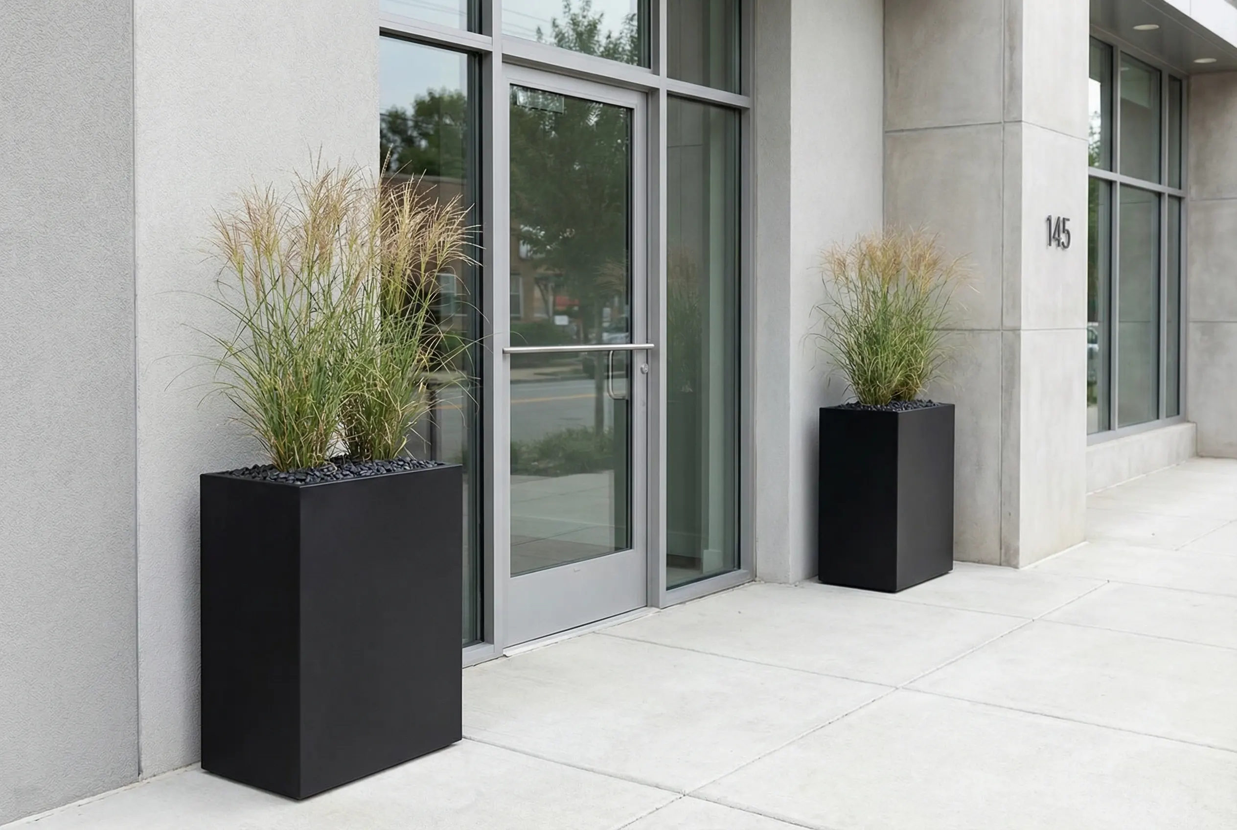 Matte black powder-coated steel planters flanking a modern commercial entrance